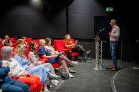 Rory Bonnar speaking at a podium to event attendees in the QFT screen 1 at Behind the Scenes at Queen's